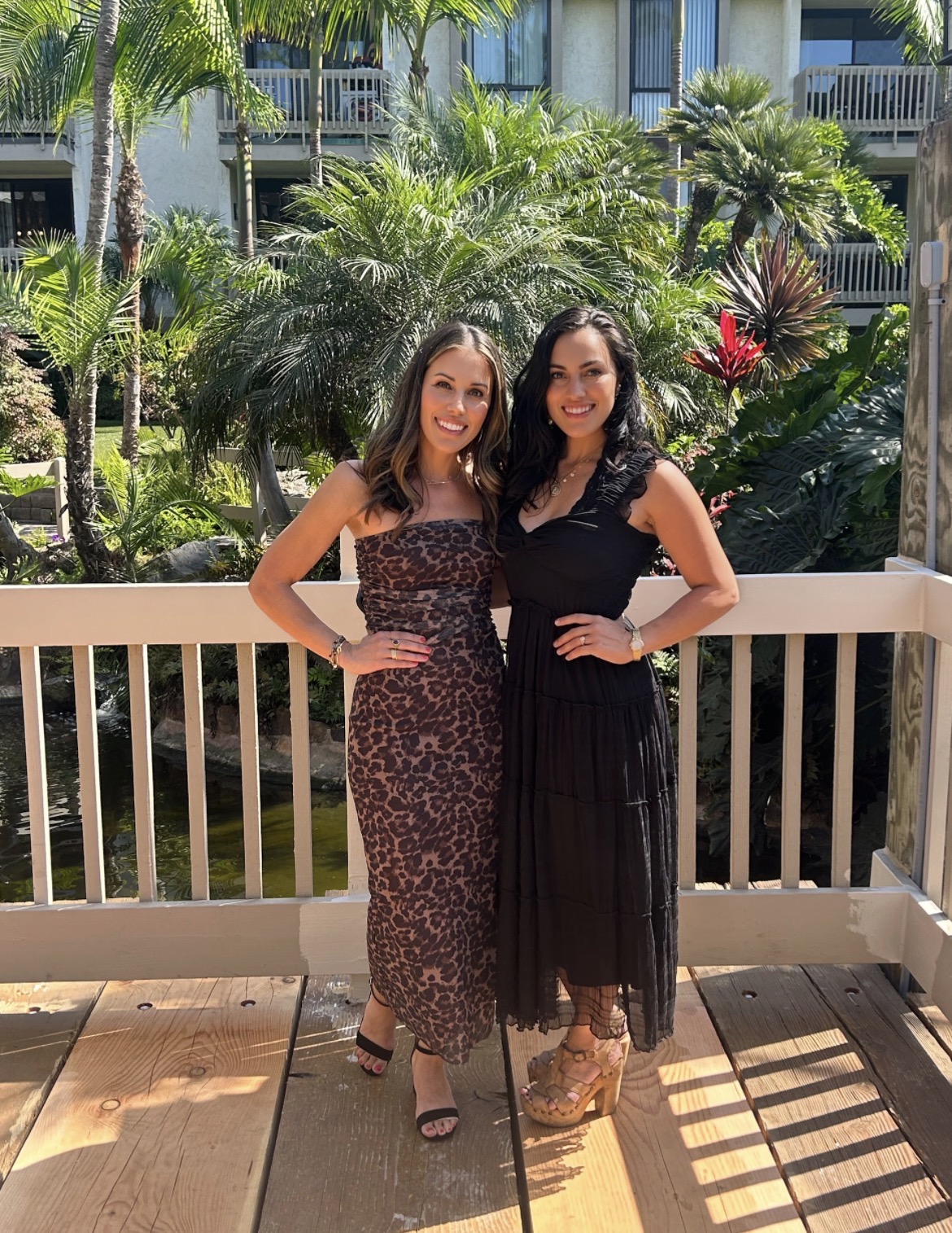 Julianna Sanchez and Cristina Nebot on a sunny wooden deck, ready to help you find your Happy Home